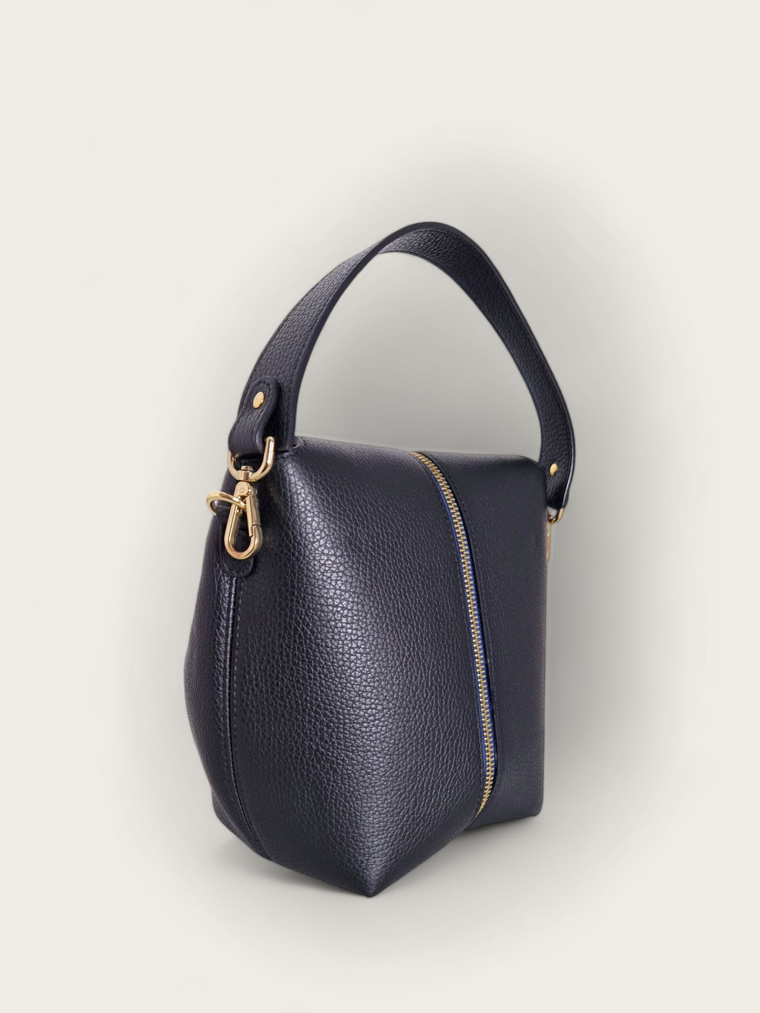 Un sac à main interchangeable noir de chez INVHERA, photo de dos, en cuir de vachette grainé doté d’un zip central doré et d’un ruban bleu nuit. Pour permettre de changer de style en un claquement de doigt. De façon unicolore ou bicolore.