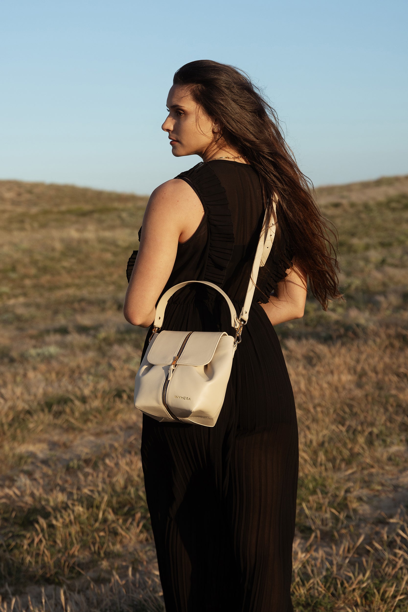 Une femme libre connectée à la nature, portant un sac à main cuir beige italien porté bandoulière amovible. Son look allure élégante vêtue d'une combinaison noire