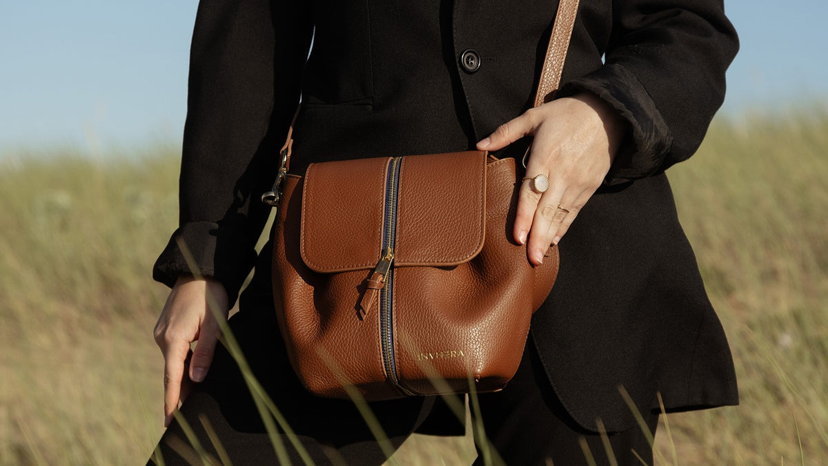 Un sac à main cuir marron porté main de chez INVHERA se balançant au main d'une femme indépendante, vidéo, montrant le changement de style, et de couleur grâce à notre système astucieux. De façon unicolore ou bicolore.