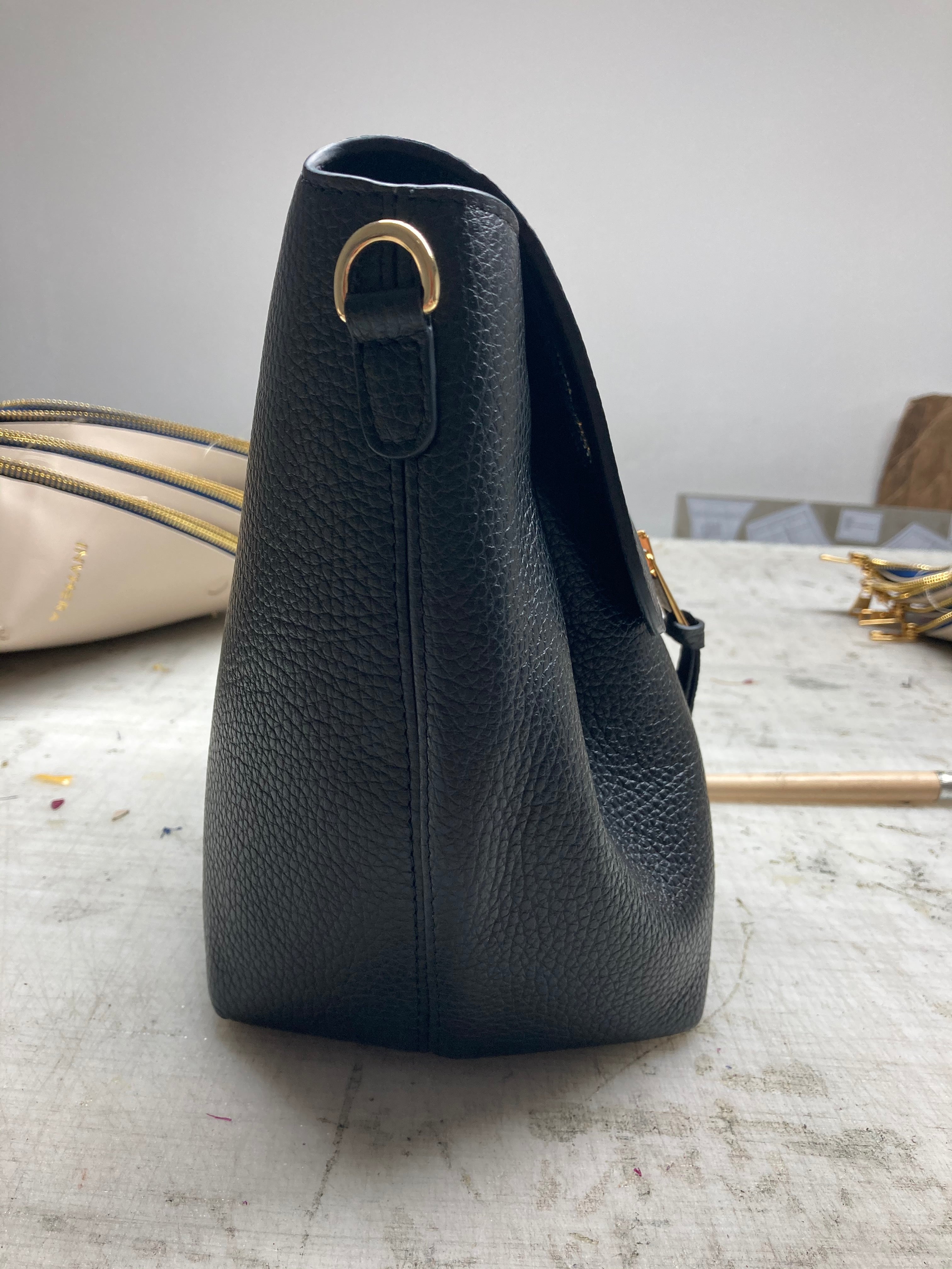 Détails côté latéral du sac à main noir en cuir de vachette italien dans notre atelier au Portugal.
